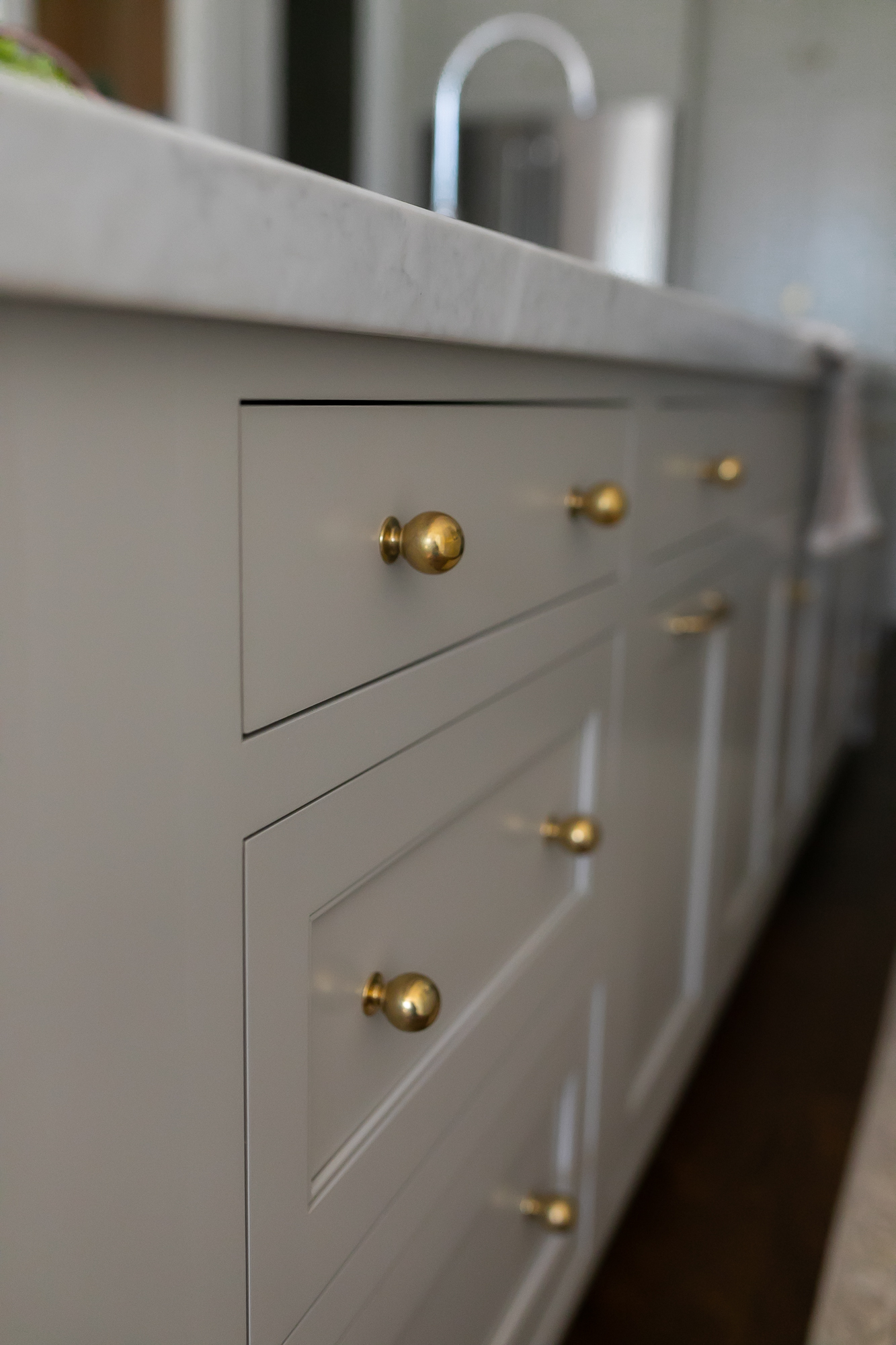 Custom kitchen island with brass knobs and marble countertop detail — J. Arthur Custom Homes cabinetry