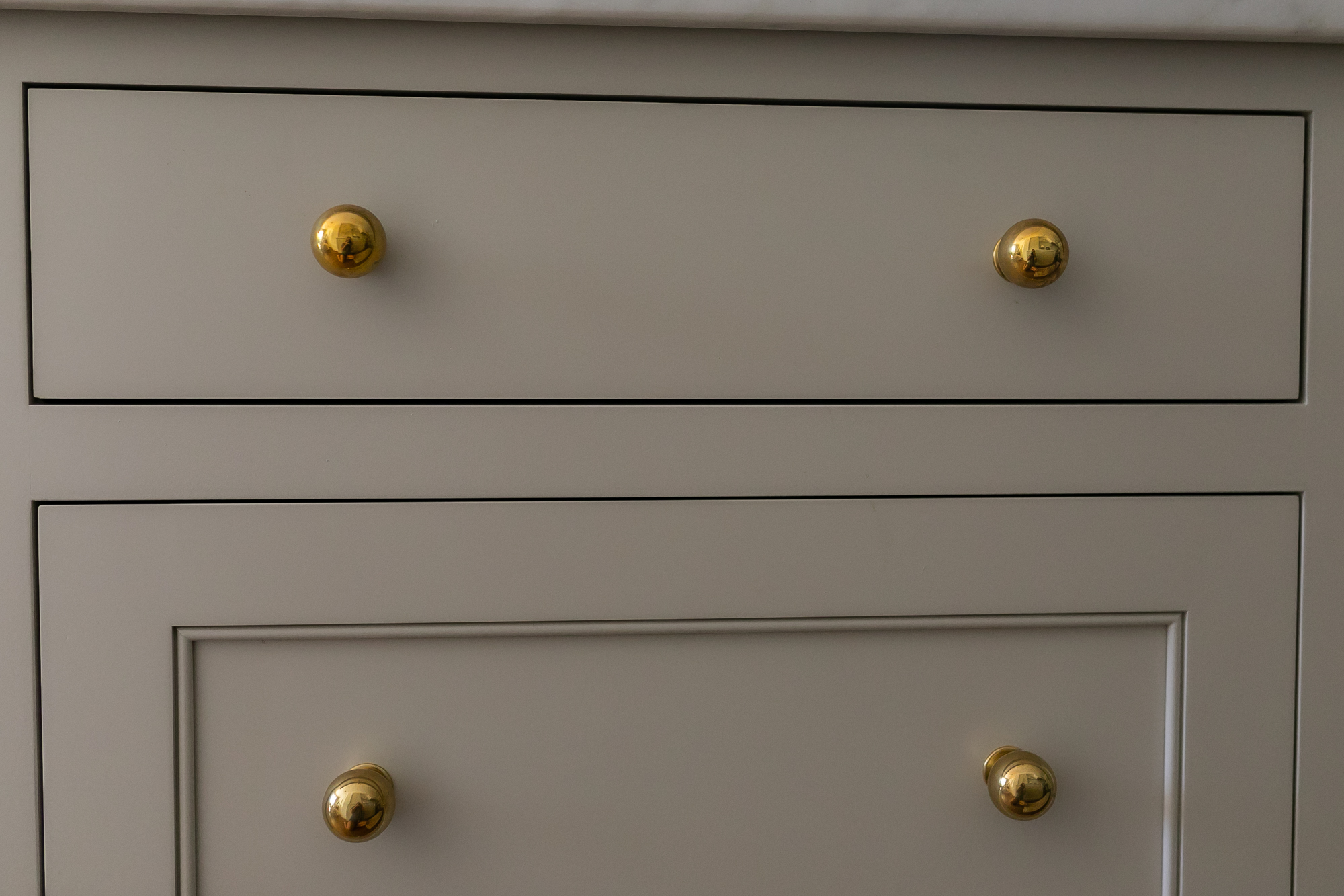 Flat-panel gray cabinet drawers with brass knobs — J. Arthur Custom Homes cabinetry craftsmanship