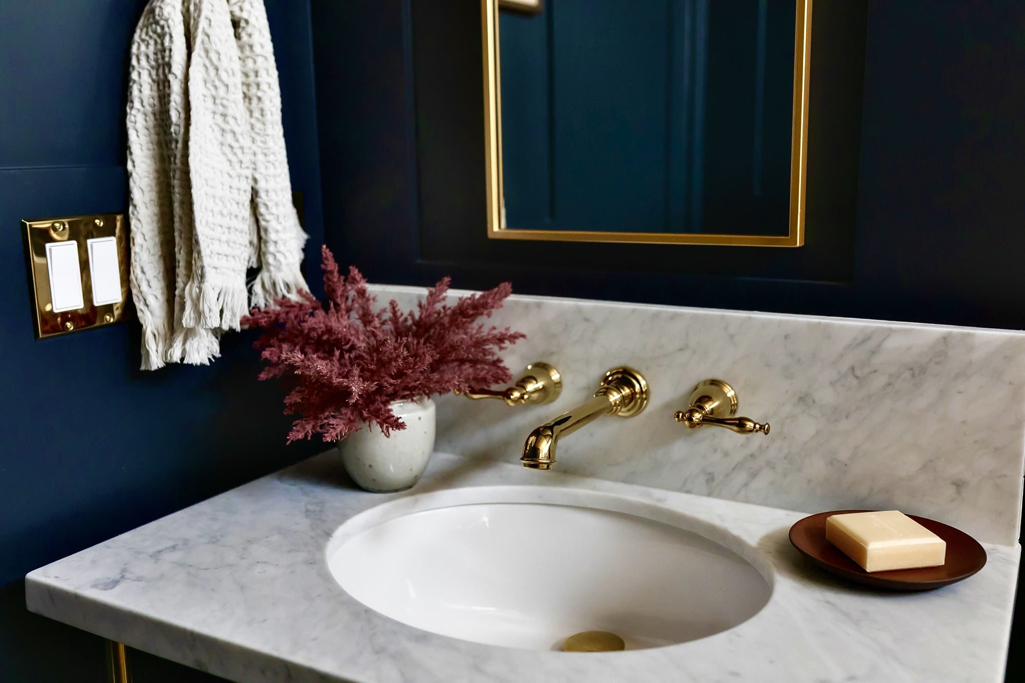 Navy bathroom vanity with marble counter and brass wall-mount faucet — J. Arthur Custom Homes